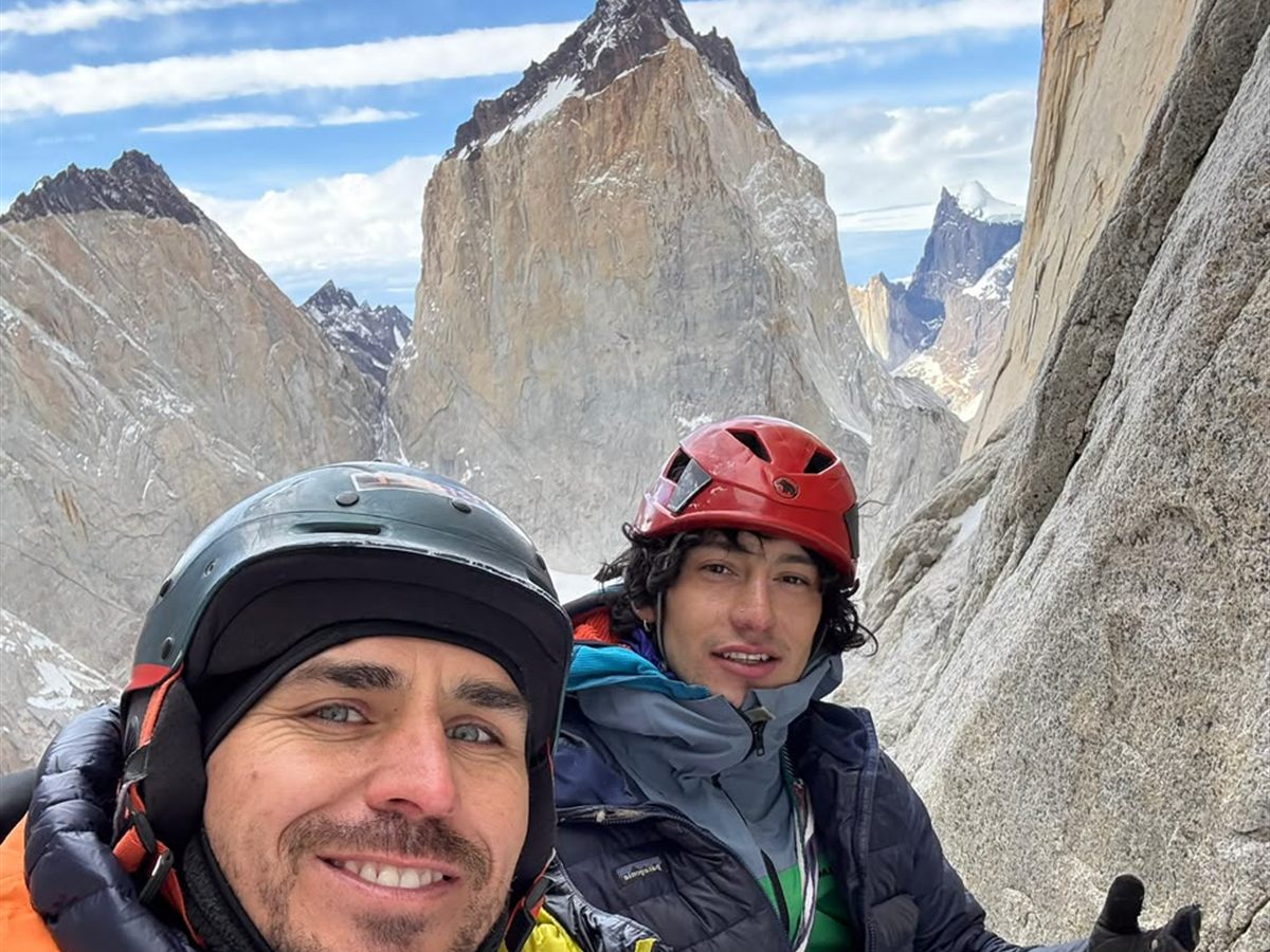 Dos escaladores en selfie de cumbre junto a una aguja de granito, Patagonia