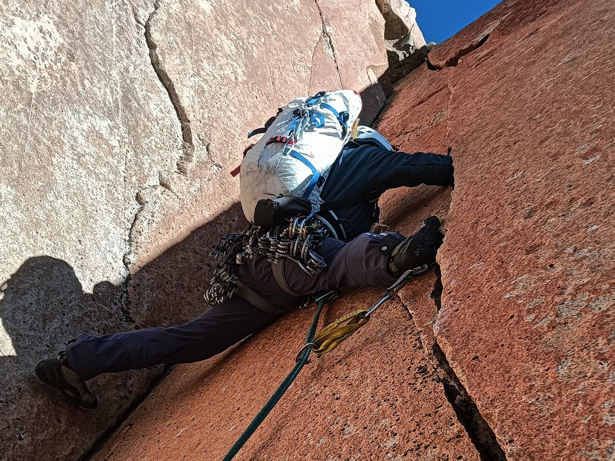 Escalada en fisura sobre granito naranja con petate de pared, Torres del Paine