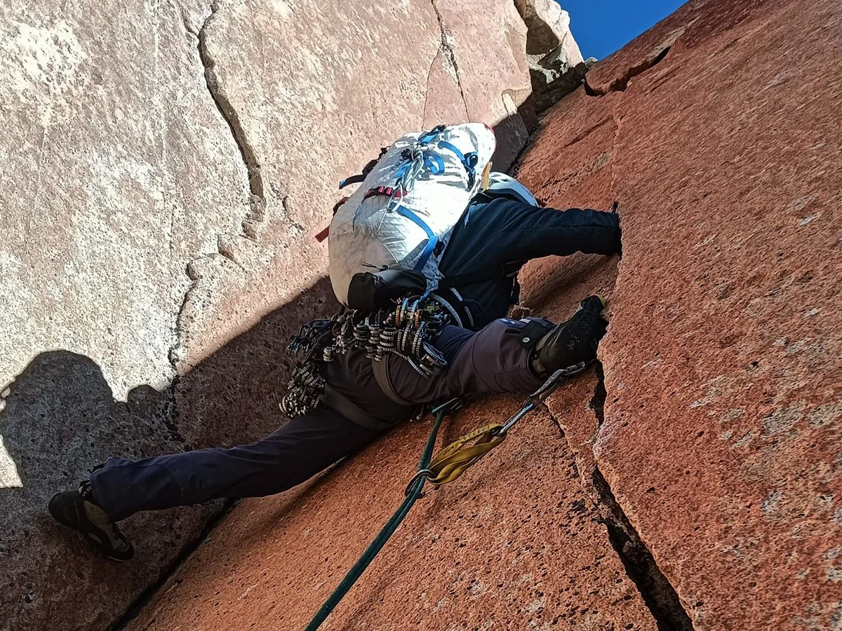 Escalada en fisura sobre granito naranja con petate de pared, Torres del Paine