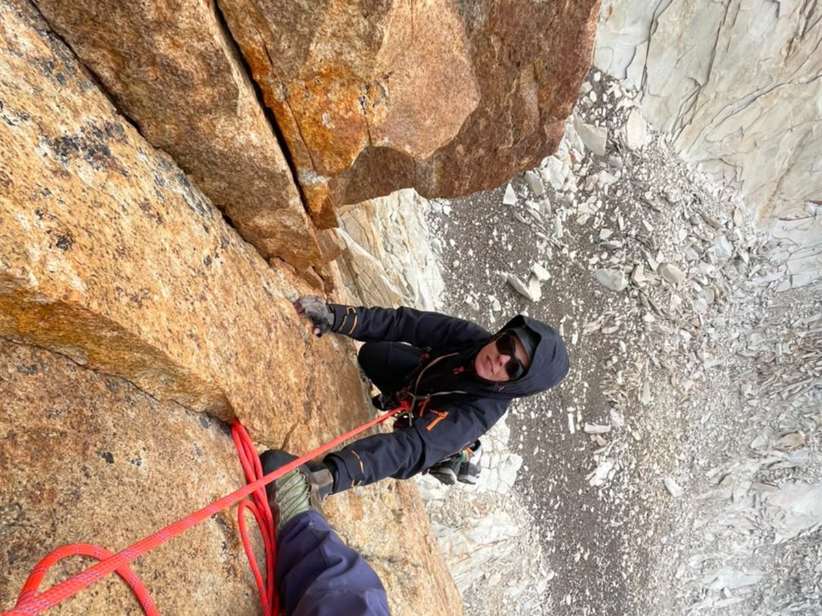 Escalador celebrando en ruta de granito dorado, Torres del Paine