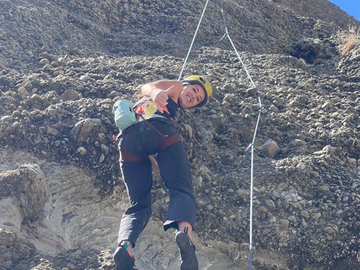 Escaladora suspendida en la cuerda con pulgar arriba en pared de conglomerado, Laguna Sofía