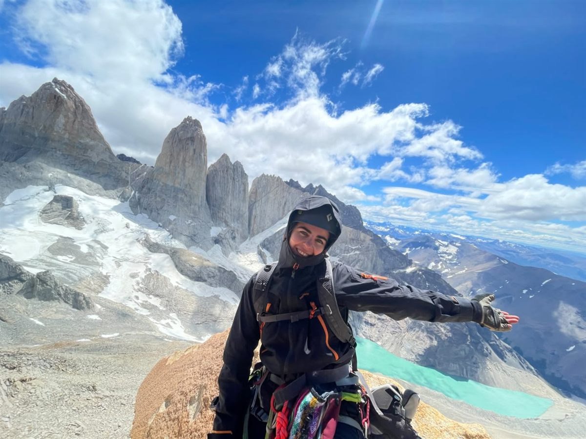 Escaladora celebrando en la cumbre frente a las Torres del Paine y su laguna turquesa